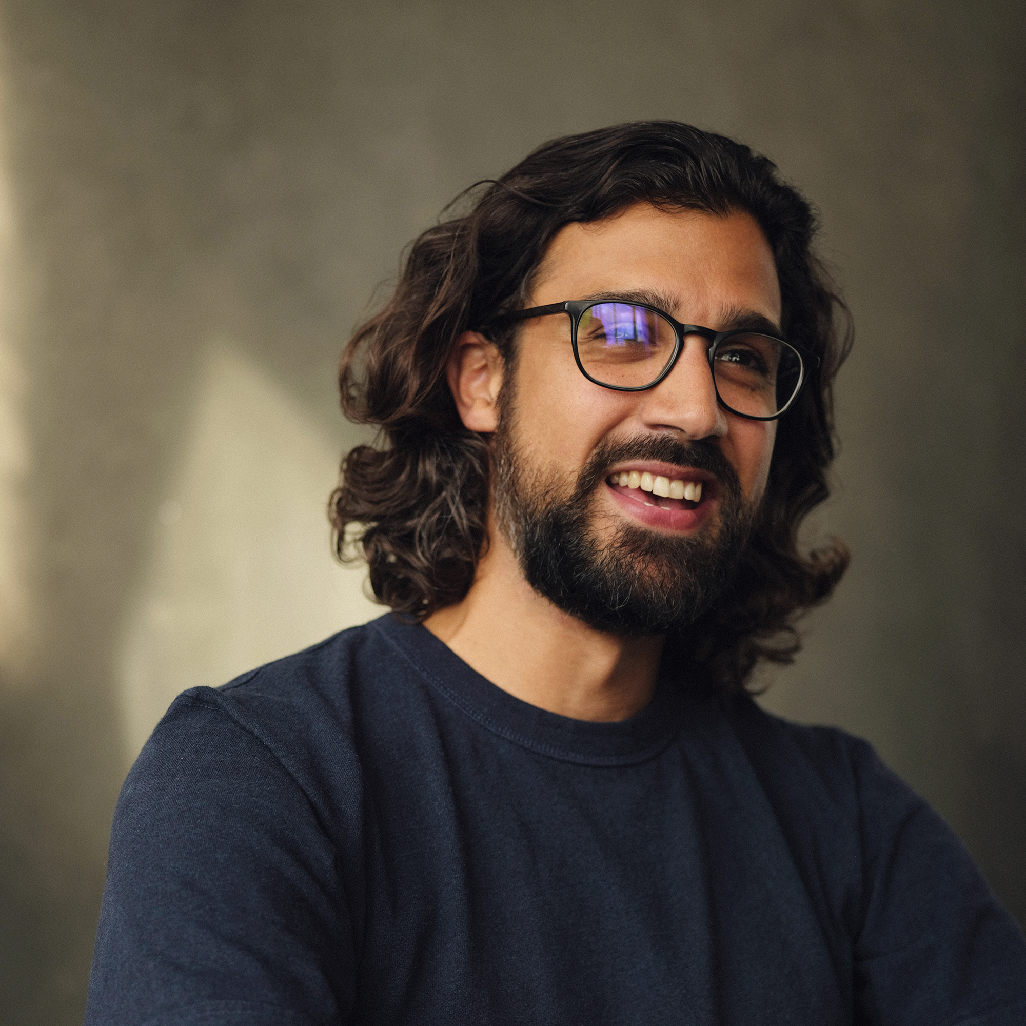 Portrait of Adam Ellison smiling against a grey background